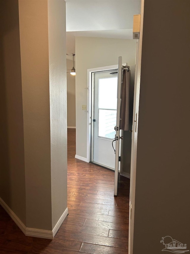 corridor featuring baseboards and dark wood finished floors