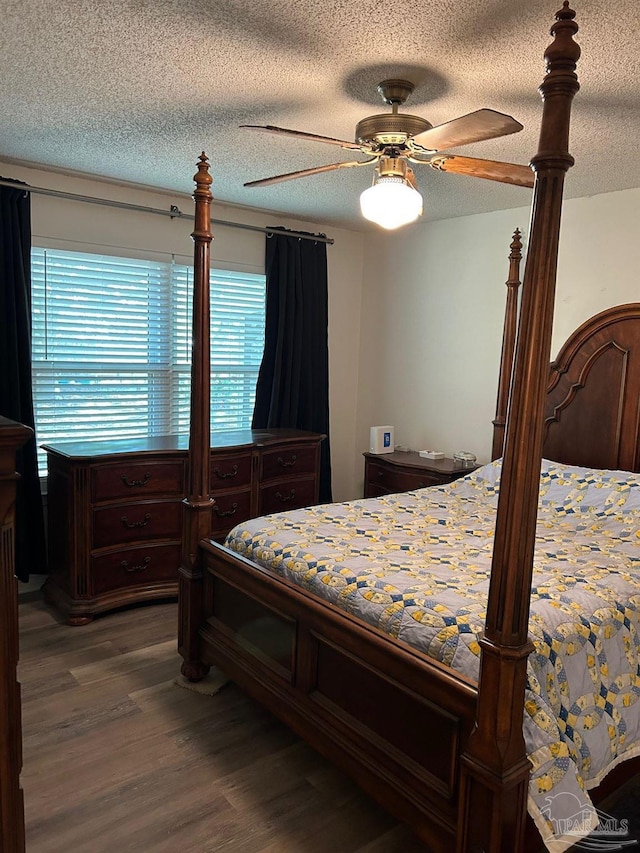 bedroom featuring ceiling fan, a textured ceiling, and dark wood finished floors