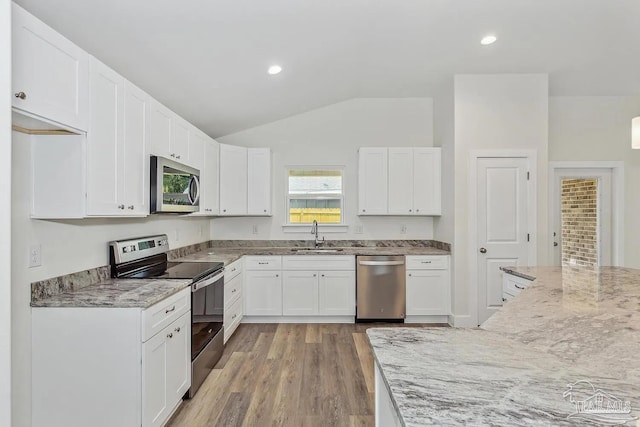 8512 Esplanade St, Navarre, FL 32566 - kitchen with stainless steel appliances, vaulted ceiling, light stone countertops, a sink, and white cabinetry