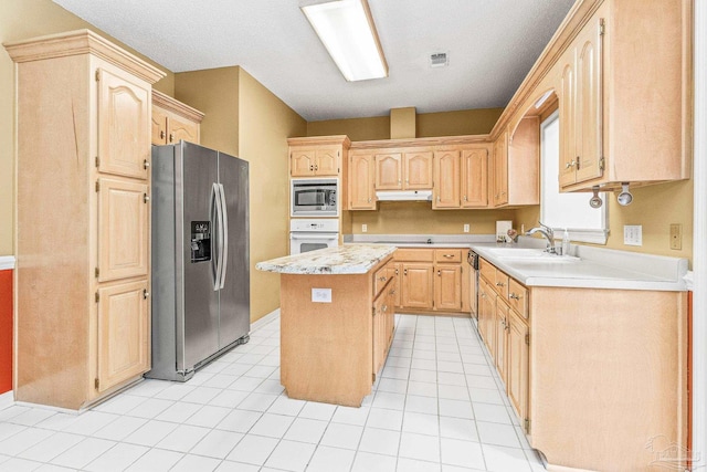 kitchen featuring appliances with stainless steel finishes, light brown cabinetry, and sink