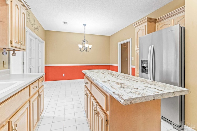 kitchen featuring a kitchen island, light brown cabinets, stainless steel fridge, and light tile patterned floors