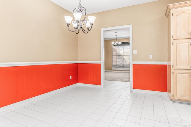 tiled spare room featuring a notable chandelier