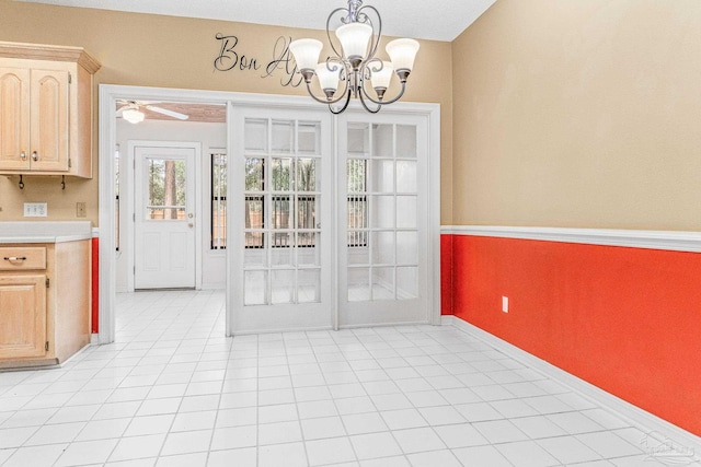 unfurnished dining area featuring ceiling fan with notable chandelier and light tile patterned floors