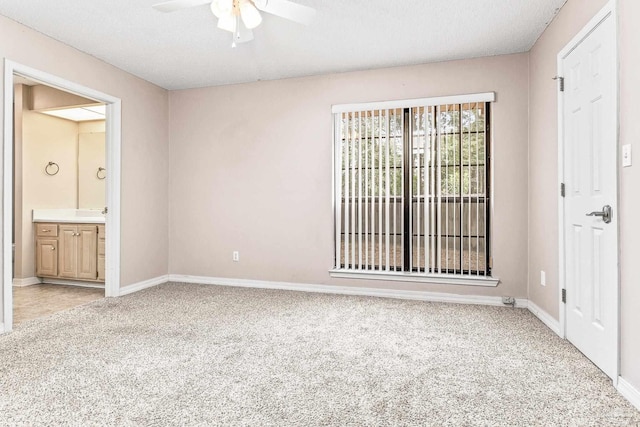 unfurnished bedroom with light carpet, a textured ceiling, ensuite bathroom, and ceiling fan