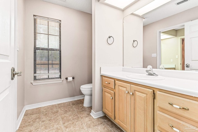 bathroom featuring vanity, toilet, a textured ceiling, and tile patterned flooring