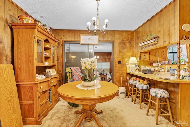 6640 Frank Reeder Rd, Pensacola, FL 32526 - carpeted dining area featuring a chandelier, wood walls, and a textured ceiling