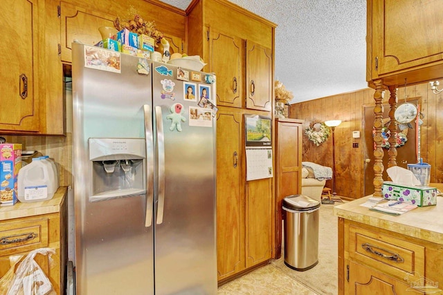 6640 Frank Reeder Rd, Pensacola, FL 32526 - kitchen featuring stainless steel refrigerator with ice dispenser, light countertops, brown cabinetry, wooden walls, and a textured ceiling