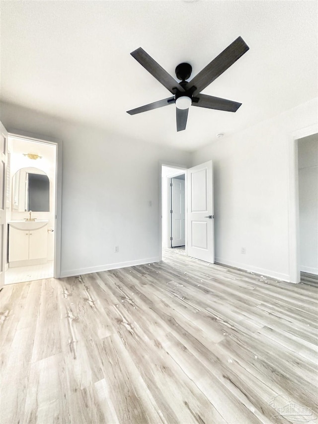 unfurnished living room with sink, ceiling fan, and light wood-type flooring