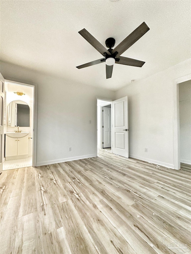 unfurnished bedroom featuring sink, a textured ceiling, light hardwood / wood-style floors, and ensuite bath