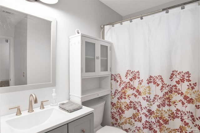 bathroom featuring vanity, curtained shower, and toilet