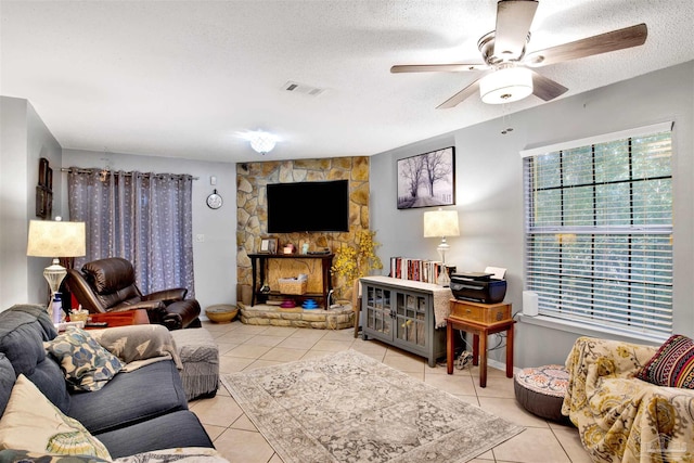 living room with ceiling fan, light tile patterned floors, and a textured ceiling