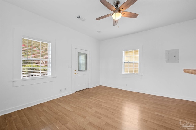 unfurnished room with ceiling fan, electric panel, and light wood-type flooring