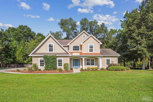 view of front of house featuring a standing seam roof, fence, and a front lawn