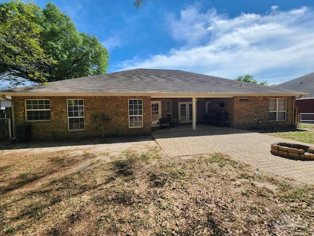 back of house with a patio area, an outdoor fire pit, a shingled roof, and brick siding