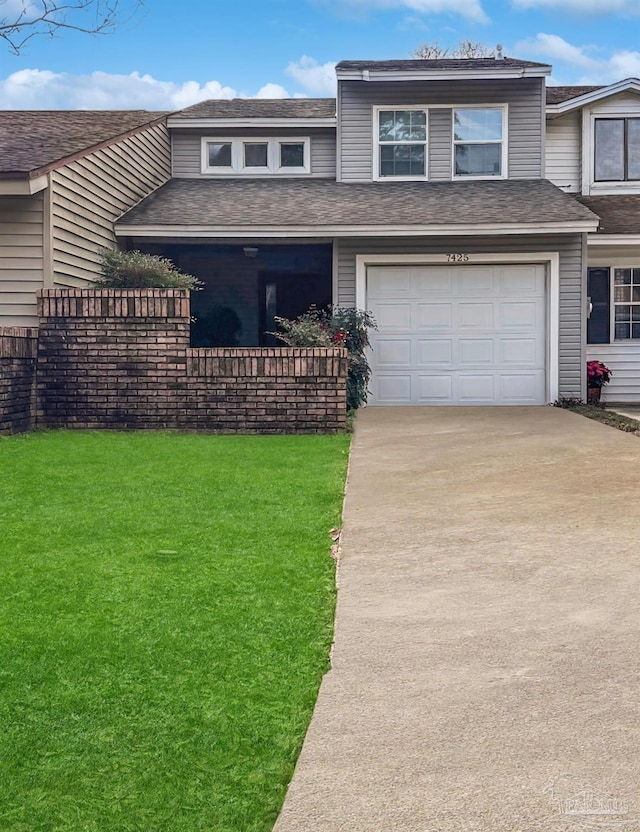 view of front of house featuring a front yard, driveway, a shingled roof, and an attached garage