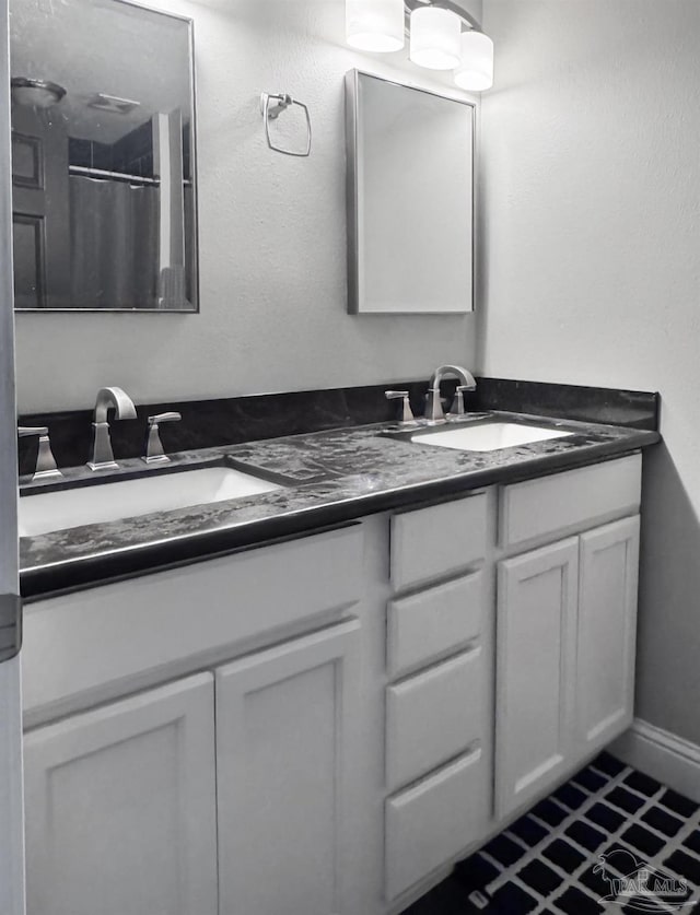 bathroom with baseboards, double vanity, and a sink
