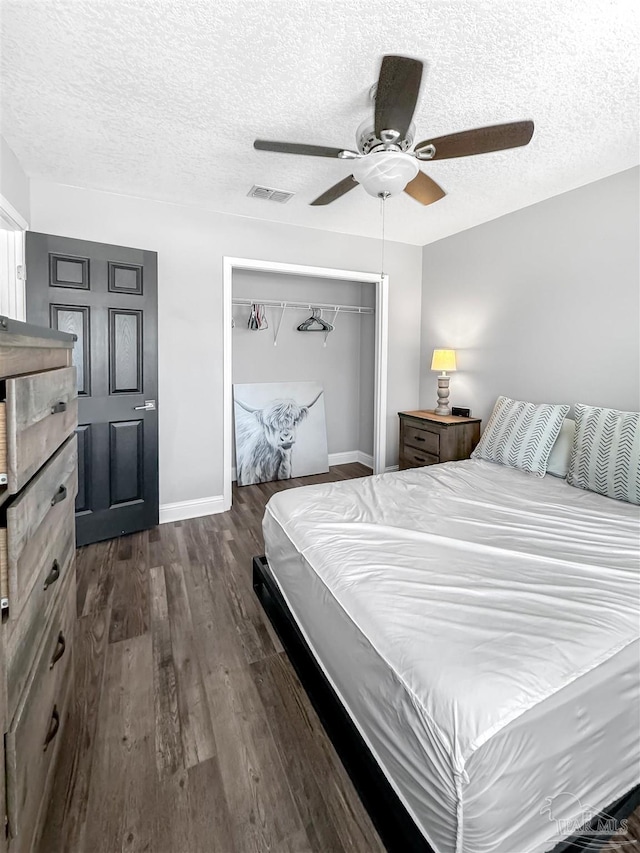 bedroom with a closet, a textured ceiling, visible vents, ceiling fan, and dark wood-type flooring