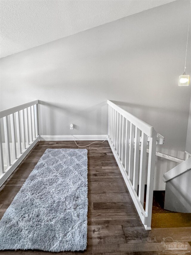 stairway with a textured ceiling, baseboards, and wood finished floors