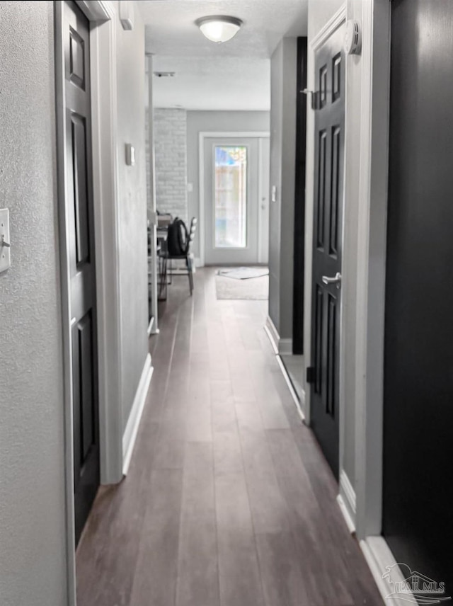 hallway featuring baseboards and wood finished floors