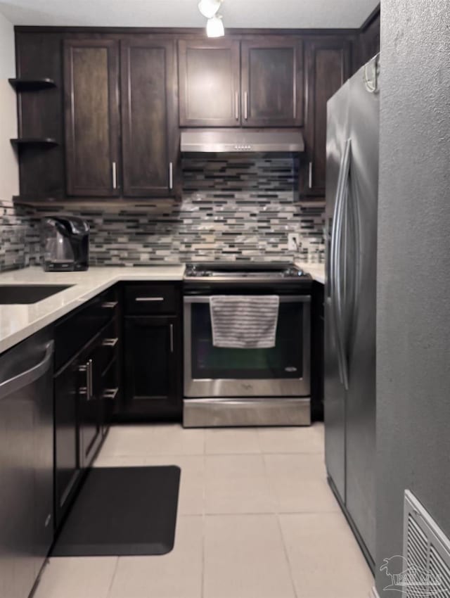 kitchen with backsplash, light countertops, under cabinet range hood, and appliances with stainless steel finishes