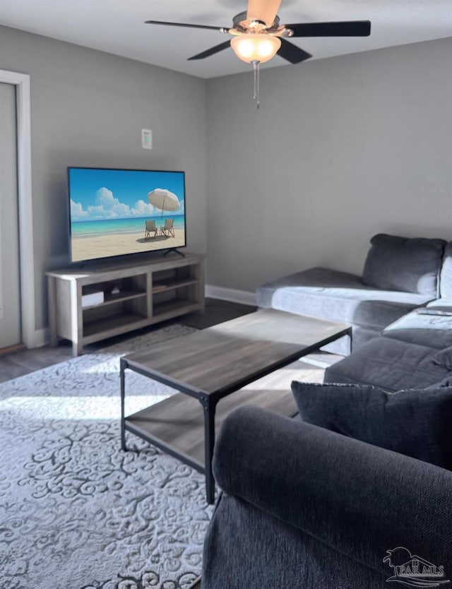 living area with baseboards, ceiling fan, and wood finished floors
