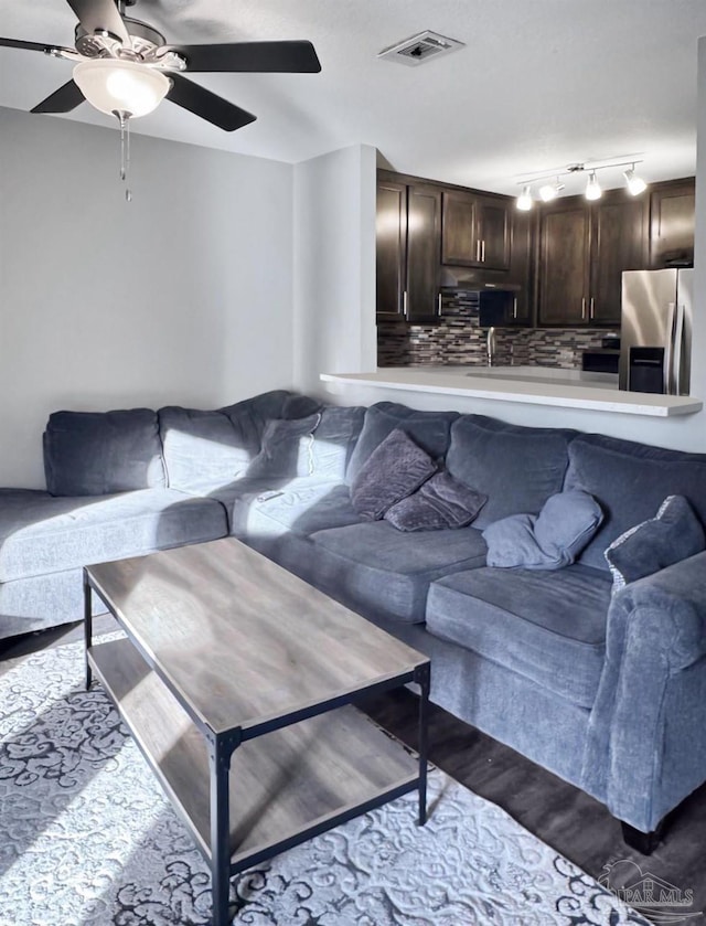 living area featuring ceiling fan, visible vents, and wood finished floors
