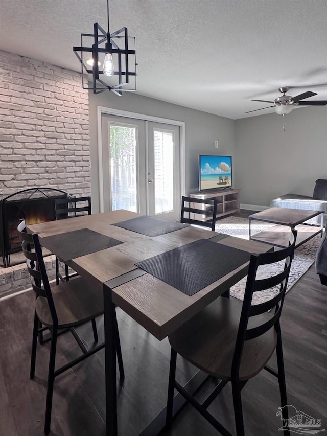 dining room with dark wood-type flooring, a textured ceiling, french doors, and ceiling fan with notable chandelier