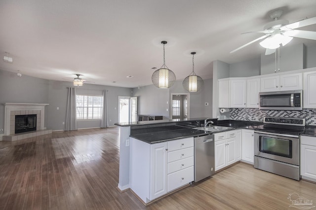 kitchen with white cabinetry, sink, decorative light fixtures, and appliances with stainless steel finishes