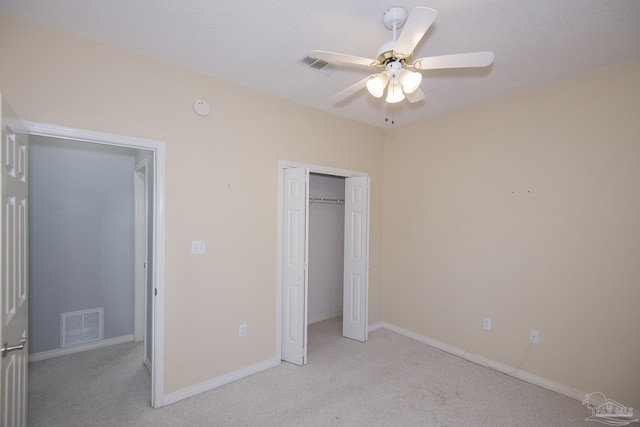 unfurnished bedroom with ceiling fan, light colored carpet, and a closet