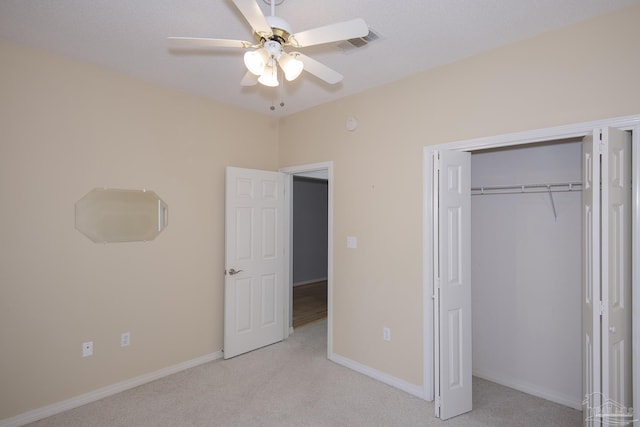 unfurnished bedroom featuring ceiling fan, a closet, and light carpet