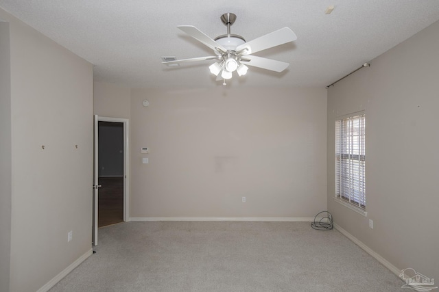 empty room with a textured ceiling, light colored carpet, and ceiling fan