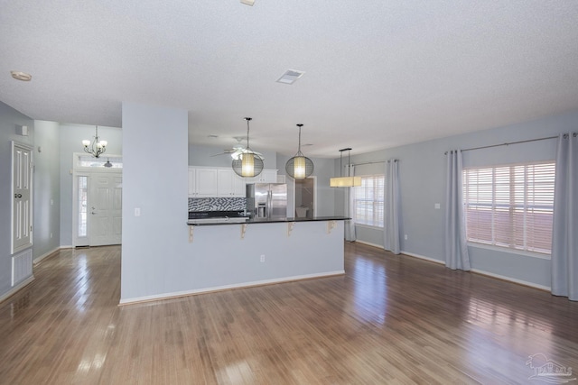 kitchen featuring hardwood / wood-style floors, backsplash, white cabinets, stainless steel refrigerator with ice dispenser, and decorative light fixtures