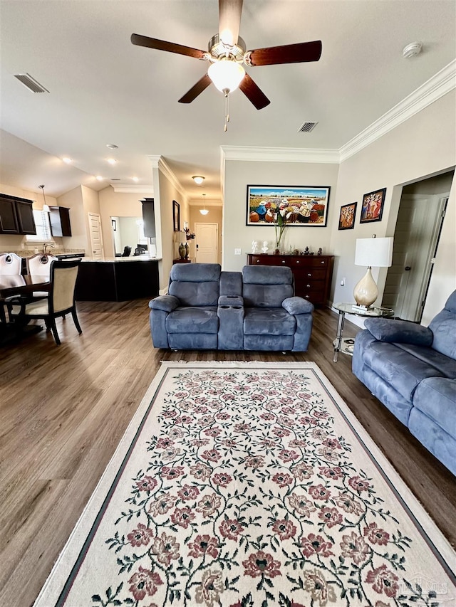 living room with ceiling fan, ornamental molding, vaulted ceiling, and hardwood / wood-style floors