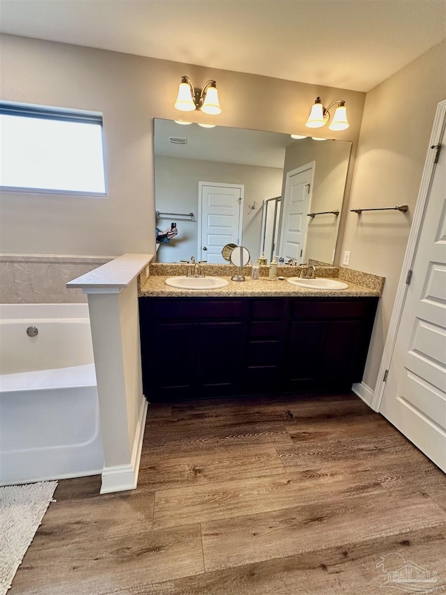 bathroom with hardwood / wood-style flooring, vanity, and a bathing tub