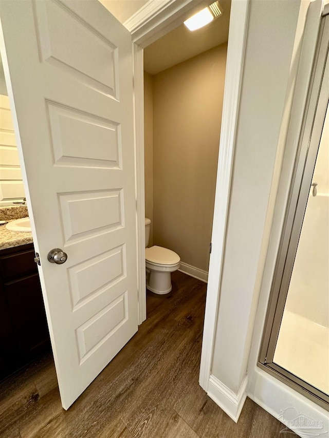 bathroom with hardwood / wood-style flooring, vanity, toilet, and walk in shower