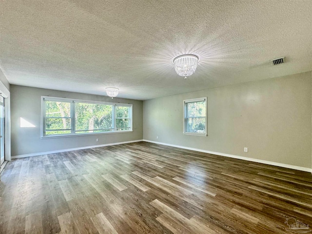 unfurnished room with hardwood / wood-style flooring, a textured ceiling, and an inviting chandelier