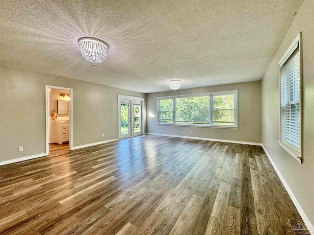 interior space with french doors, wood-type flooring, a textured ceiling, and a notable chandelier