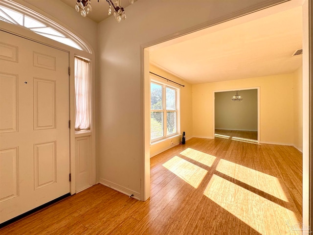 foyer entrance with light wood-type flooring and a notable chandelier