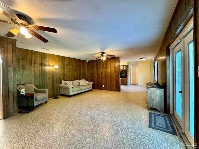 unfurnished living room with ceiling fan and wooden walls