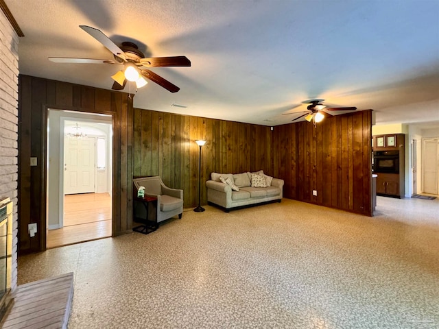 unfurnished living room with ceiling fan with notable chandelier, a brick fireplace, and wood walls