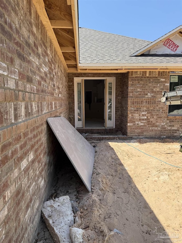 property entrance with brick siding and roof with shingles
