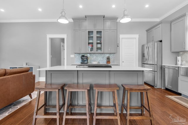 kitchen featuring gray cabinetry, appliances with stainless steel finishes, light countertops, backsplash, and a breakfast bar area
