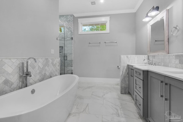 bathroom featuring double vanity, tile walls, marble finish flooring, a freestanding bath, and a stall shower