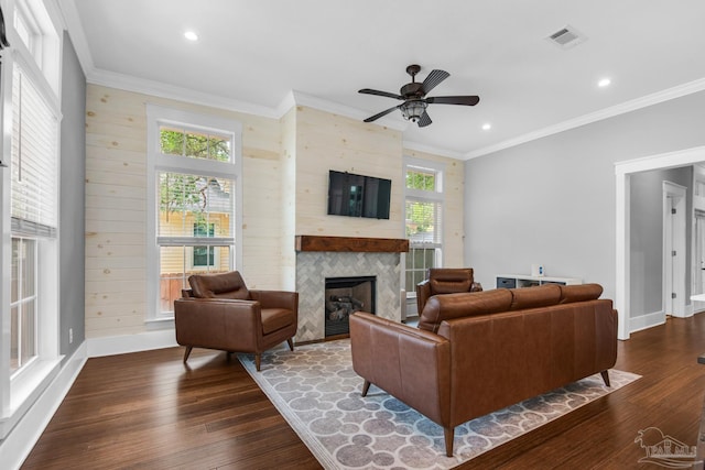 living area featuring healthy amount of natural light, a fireplace, dark wood-type flooring, ornamental molding, and recessed lighting