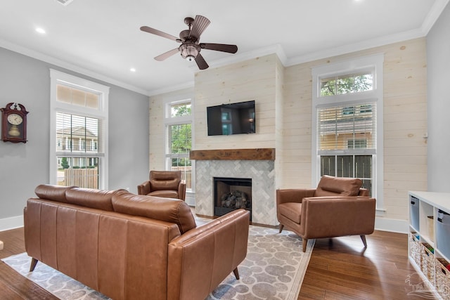 living area with wood finished floors, a large fireplace, recessed lighting, ornamental molding, and ceiling fan