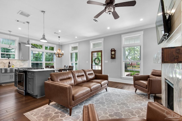 living room with plenty of natural light, crown molding, recessed lighting, a ceiling fan, and dark wood-type flooring