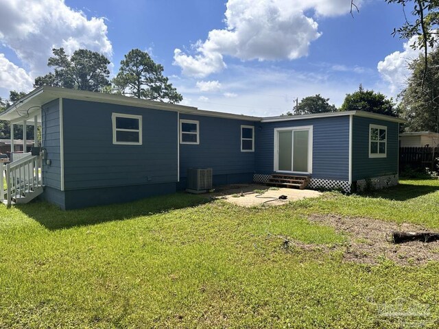 rear view of property featuring central air condition unit and a lawn