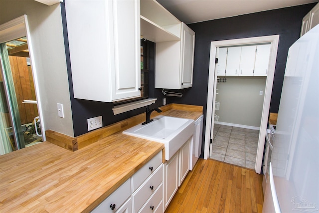 7402 Viewcrest Dr, Pensacola, FL 32504 - kitchen with a sink, butcher block countertops, white cabinetry, light wood-style floors, and white appliances