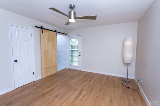 7402 Viewcrest Dr, Pensacola, FL 32504 - empty room with a ceiling fan, light wood-style floors, a barn door, and baseboards