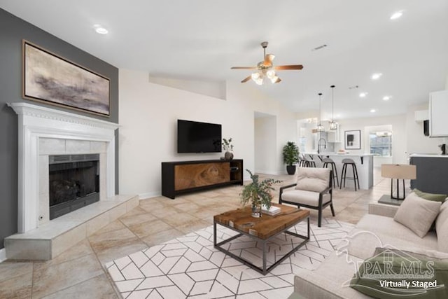 living room featuring a tiled fireplace, ceiling fan, and sink